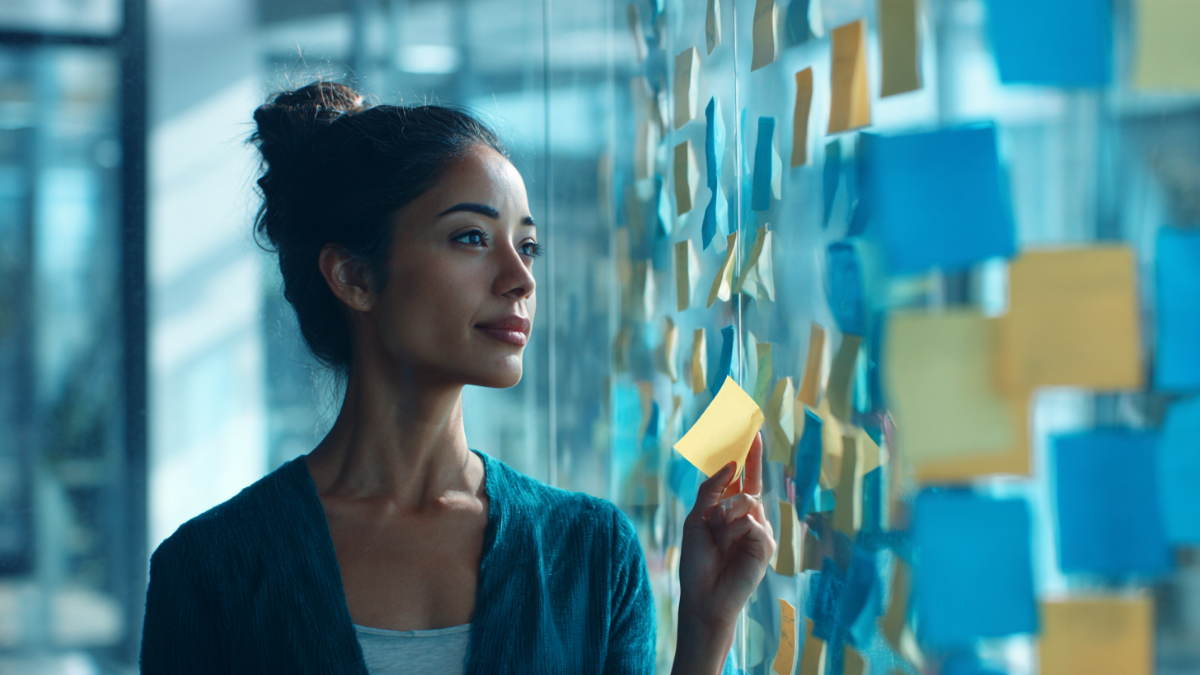 Mujer ante un muro de cristal con notas adhesivas, algunas a punto de caerse